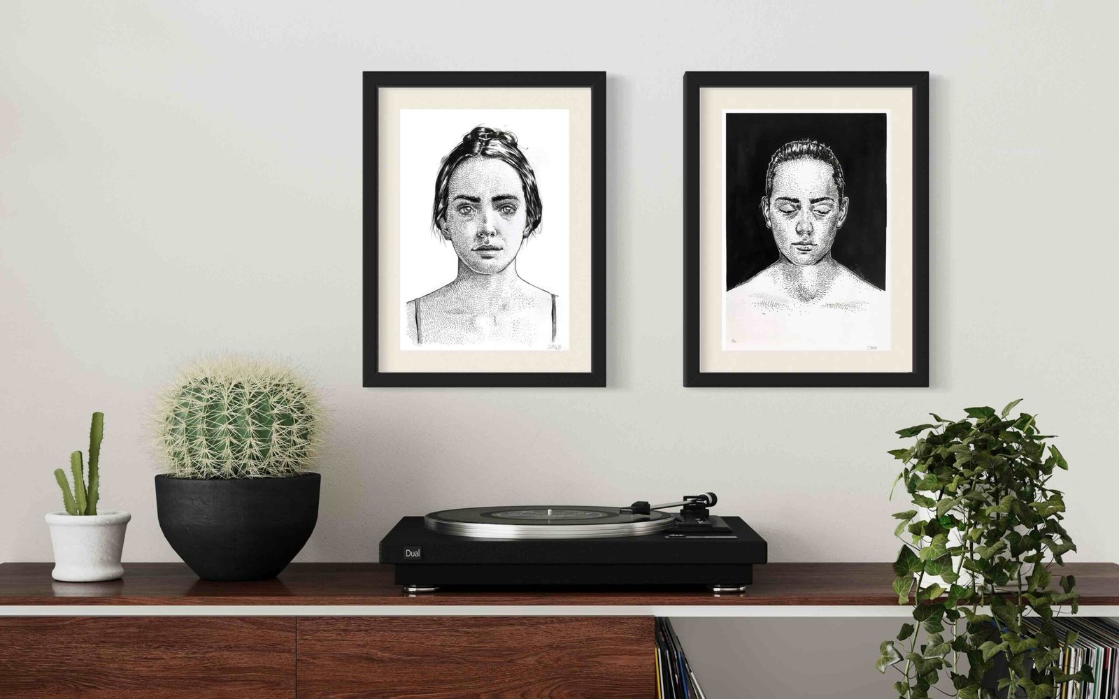 Two ink portraits by Dario Moschetta above a turntable console