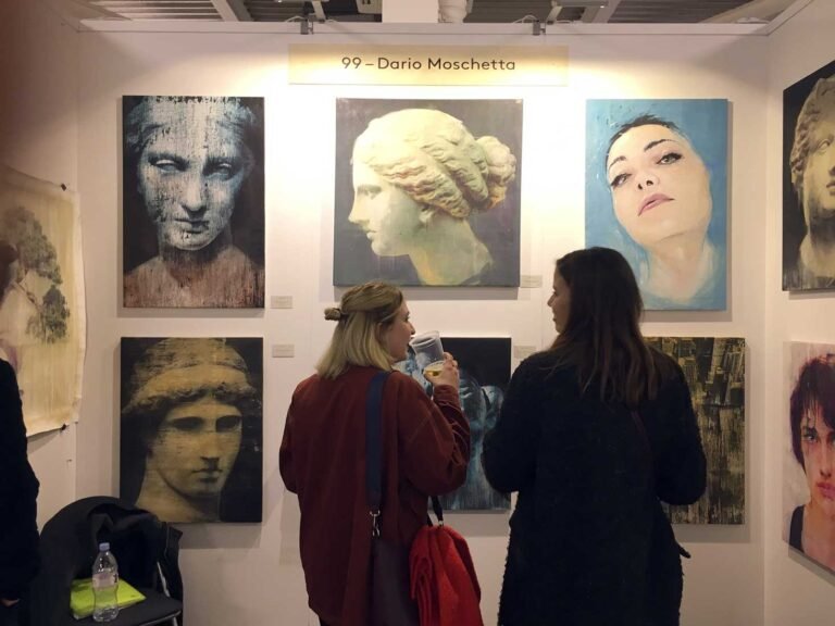 Visitors looking at Ancient Beauty works and portraits at booth 99, The Other Art Fair London 2019