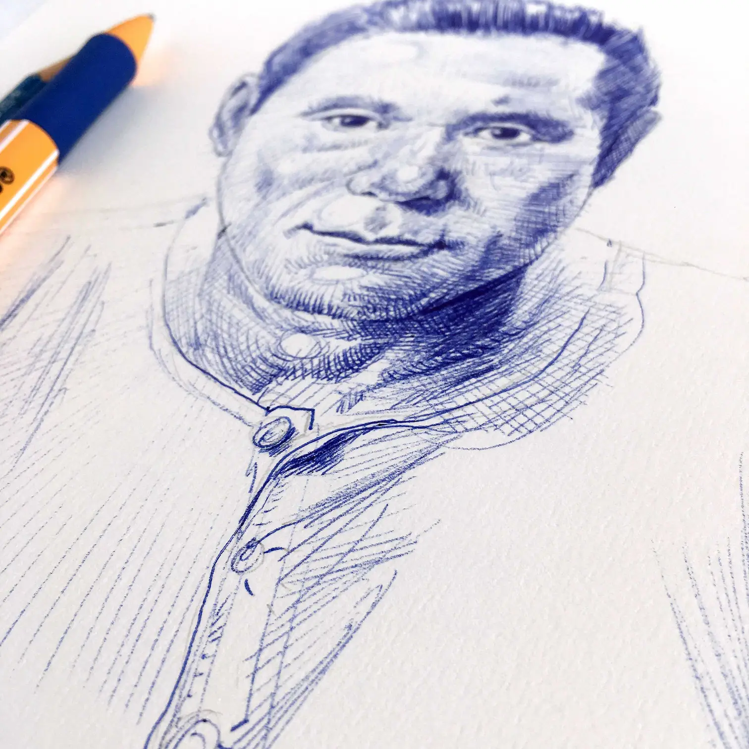 Detailed male ballpoint portrait drawing in blue ink showing face and shirt