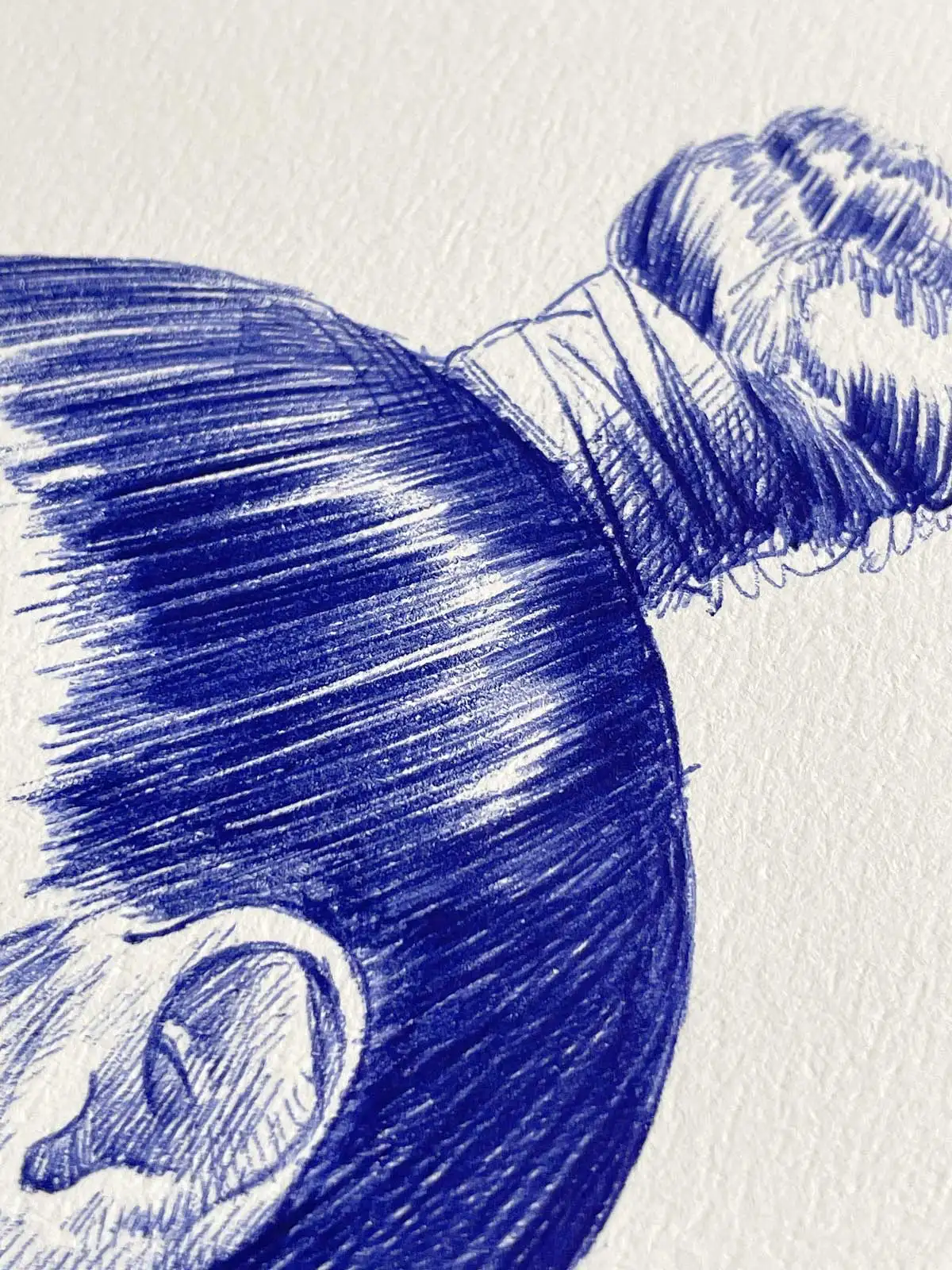 Close-up of a female portrait in blue ballpoint ink on A4 paper, showing the details of the hair and ear