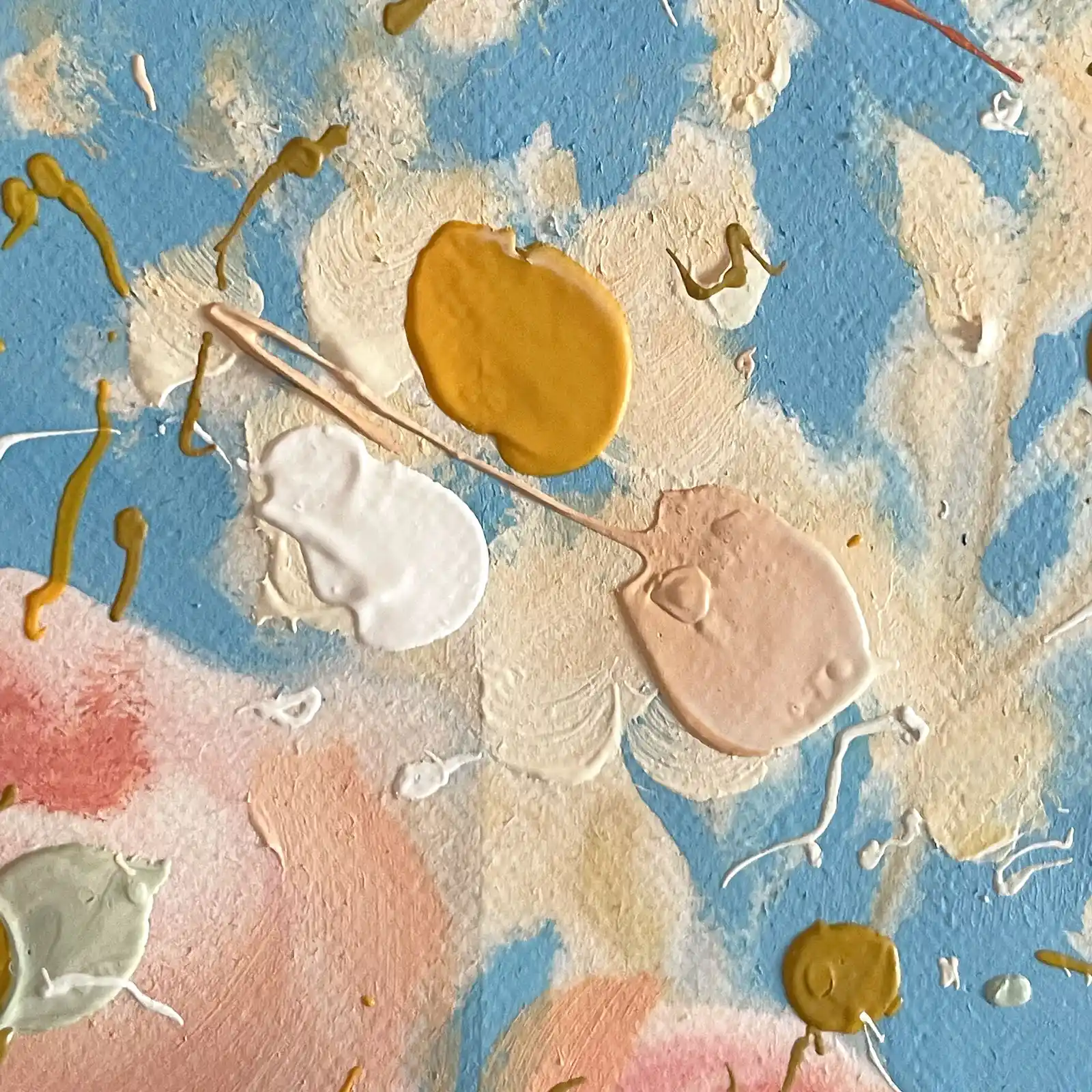 Close up of cream flowers against a blue sky with raised drops of mustard, white and peach paint
