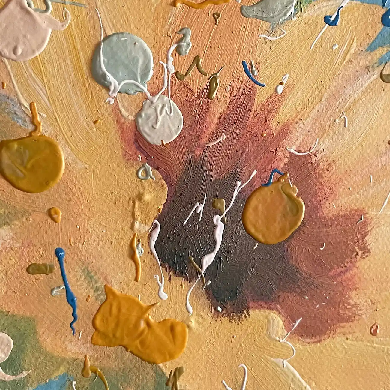 Close up of an orange flower with a dark brown center and raised drops of mustard, grey and white paint